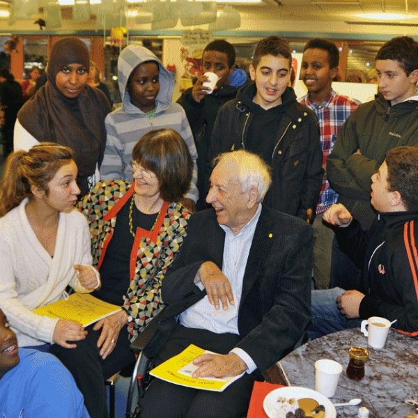 Tomas Tranströmer omgiven av barn på Rinkeby bibliotek.