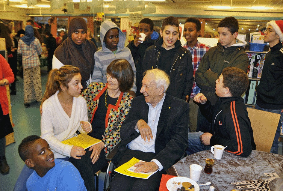 Tomas Tranströmer omgiven av barn på Rinkeby bibliotek.